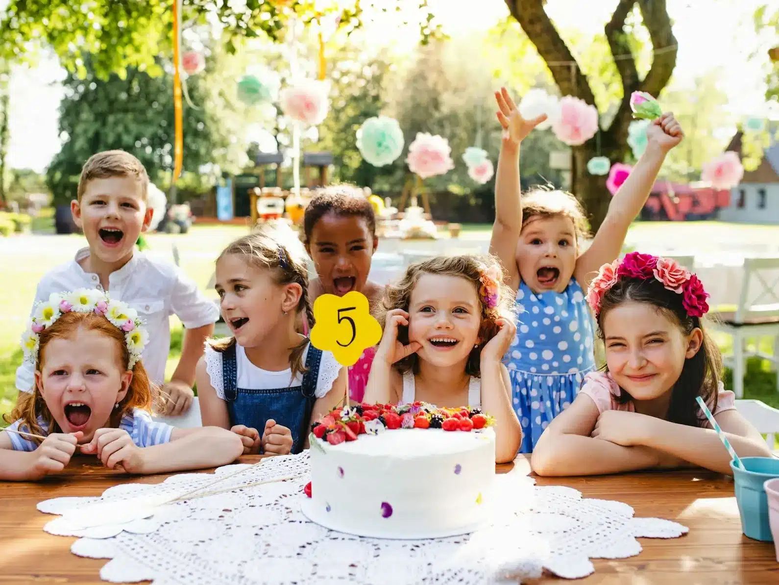 a group of kids sitting around a table with a cake