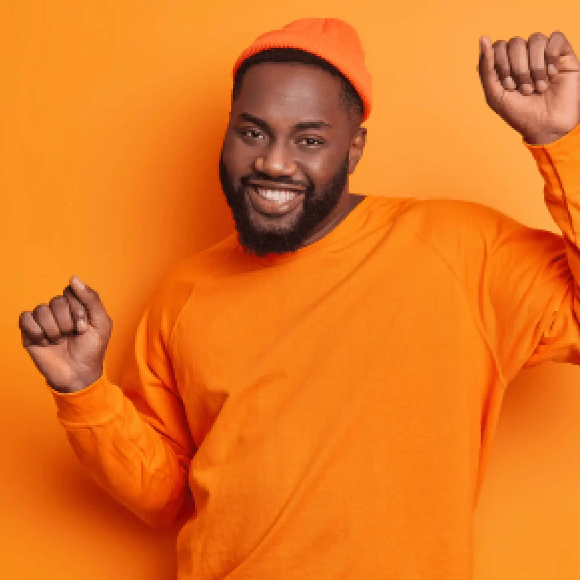 a man in an orange shirt and hat with his hands up
